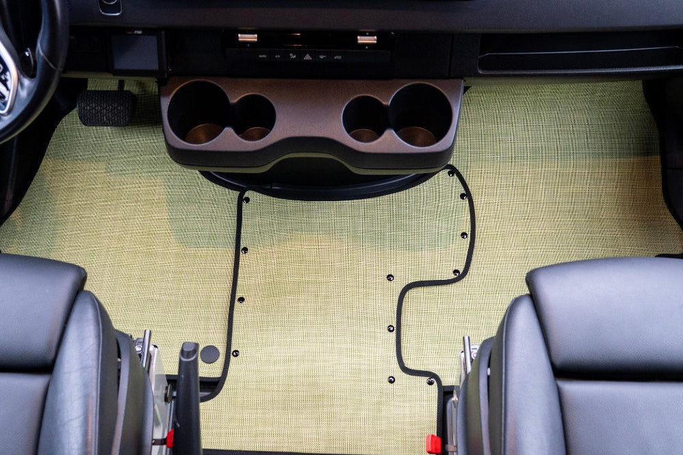 Car interior with a custom floor mat and cup holder installation.