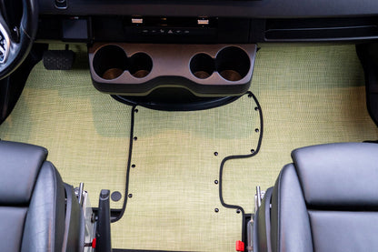 Car interior with a custom floor mat and cup holder installation.