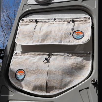 Nomad Vanz Rear Door Storage Pocket System in Cirrus Sand camo installed on a Sprinter rear door showing two upper rectangular pockets and two lower rounded pockets with toggle closures and Nomad Vanz logo patches