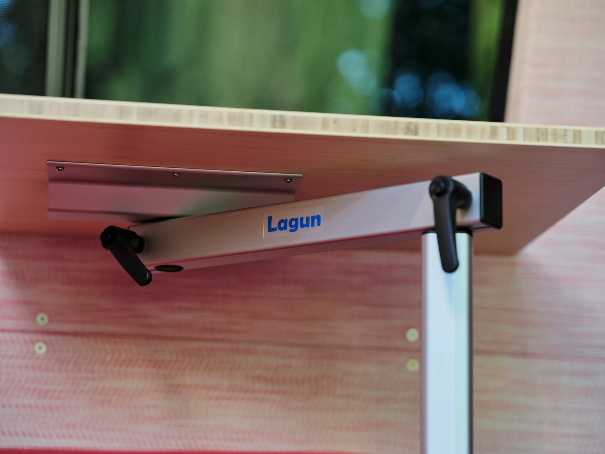 Close-up of a Lagun swivel table mount and bamboo tabletop in the coral-toned interior of the Nomad Vanz Klickitat Sprinter