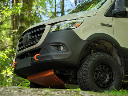 Close-up of a Nomad Vanz Sprinter 4x4 front corner showing BFGoodrich all-terrain tire, black off-road wheel, and front skid plate
