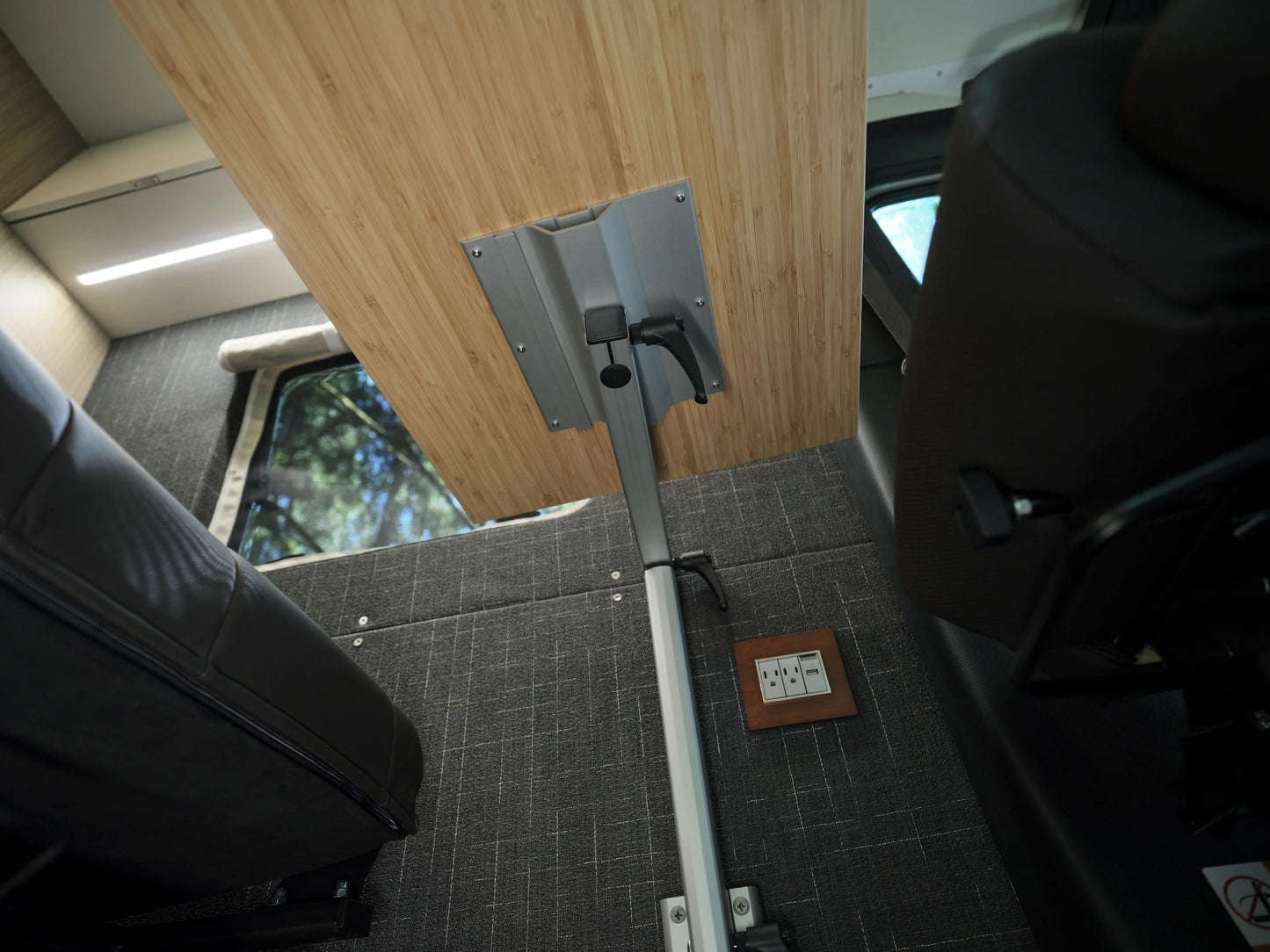 Close-up of a Lagun swivel table arm and adjustment lever mounted under a bamboo tabletop in a Nomad Vanz Sprinter