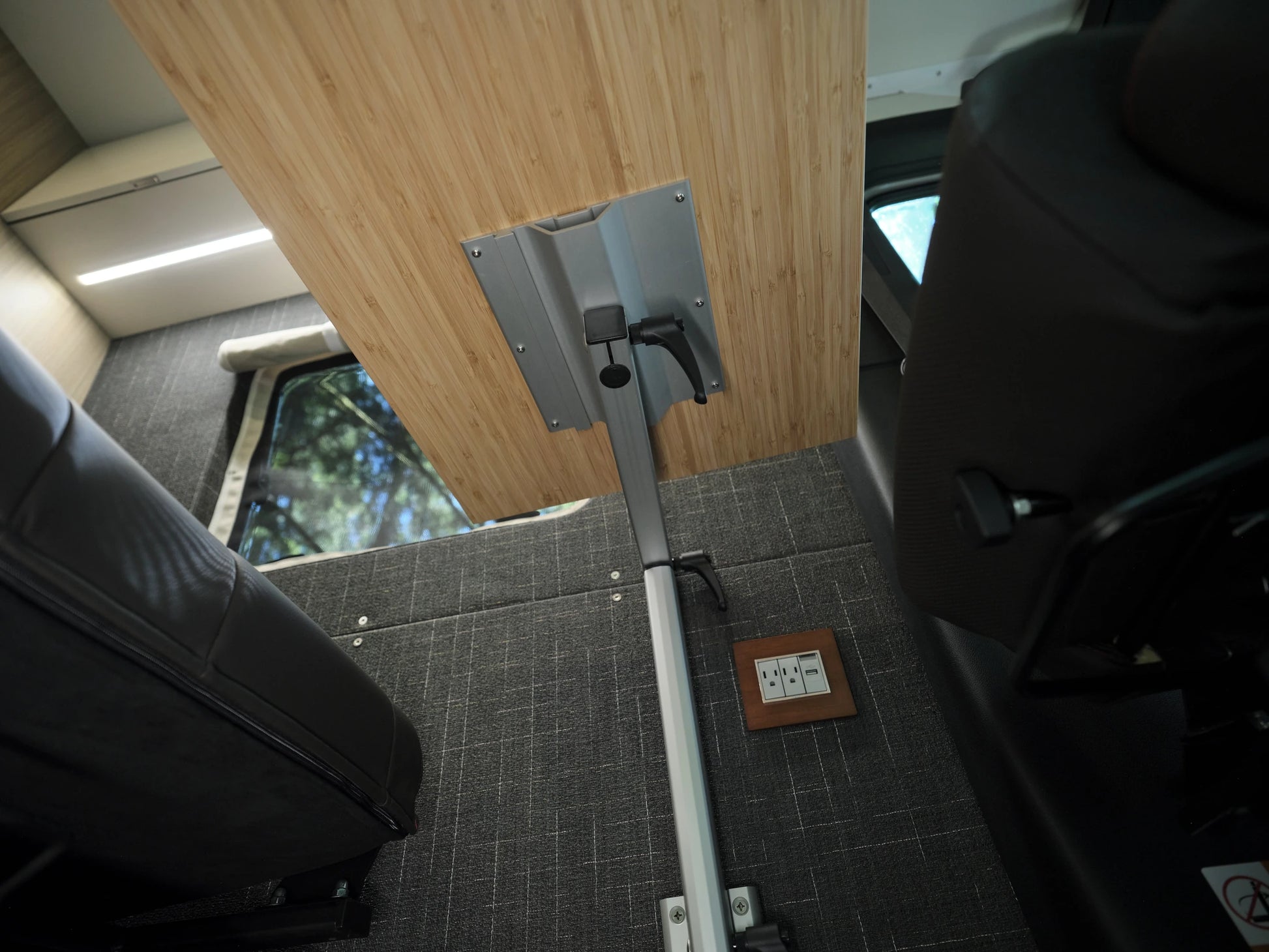 Close-up of a Lagun swivel table arm and adjustment lever mounted under a bamboo tabletop in a Nomad Vanz Sprinter
